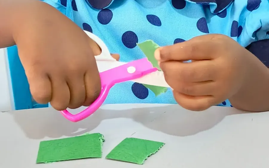 A child carefully cutting paper with safety scissors