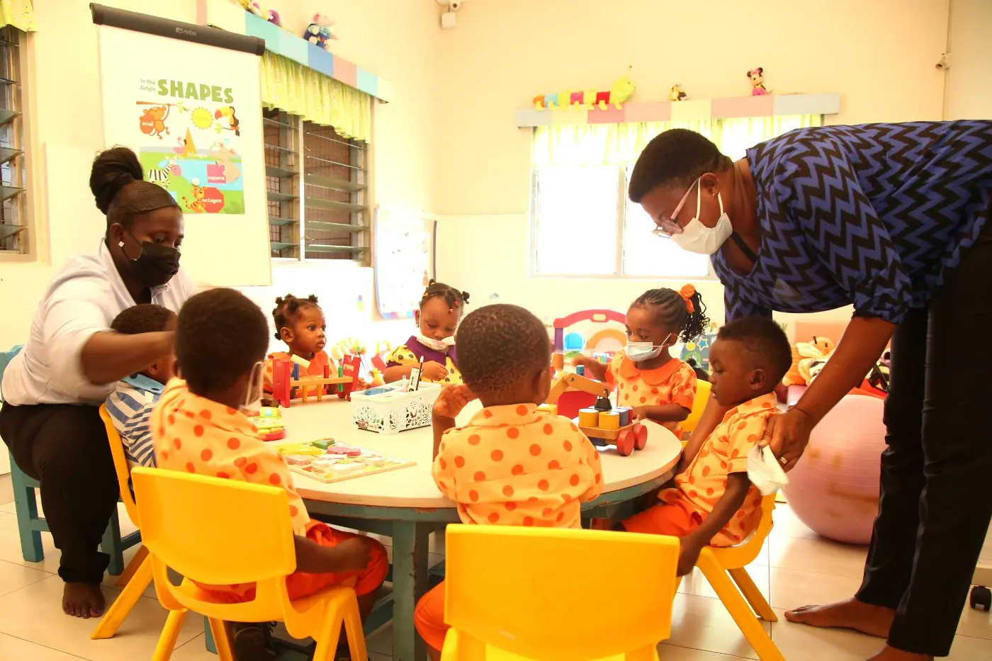 Children in the crèche playing at a low table with their carers