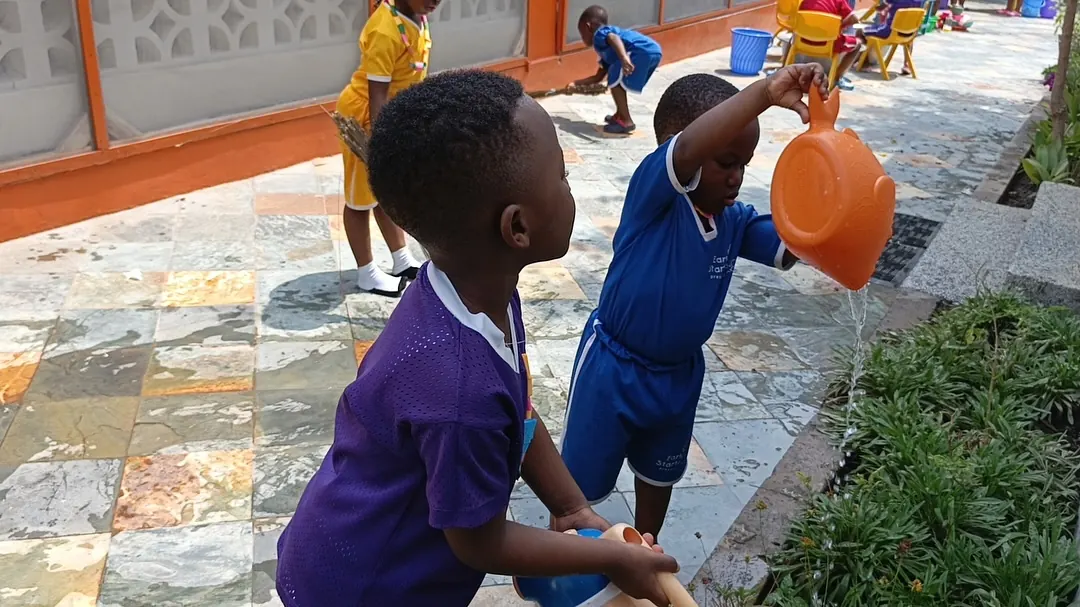 Two boys watering the school garden with watering cans