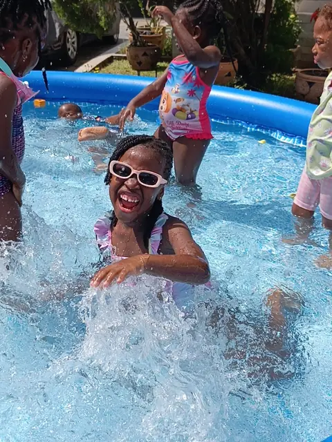 A smiling girl splashing in the paddling pool at Early Starters