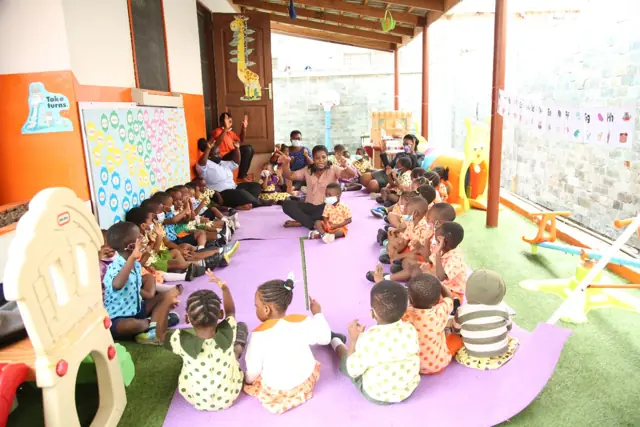 Children sitting together on a purple mat for story time