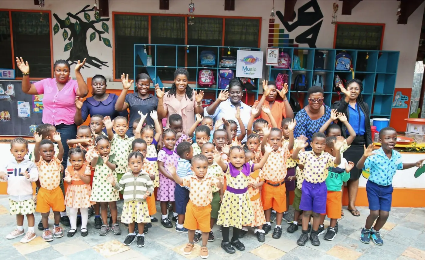 Early Starters Preschool children in polka-dot uniforms waving with their teachers in the school courtyard in Labone, Accra